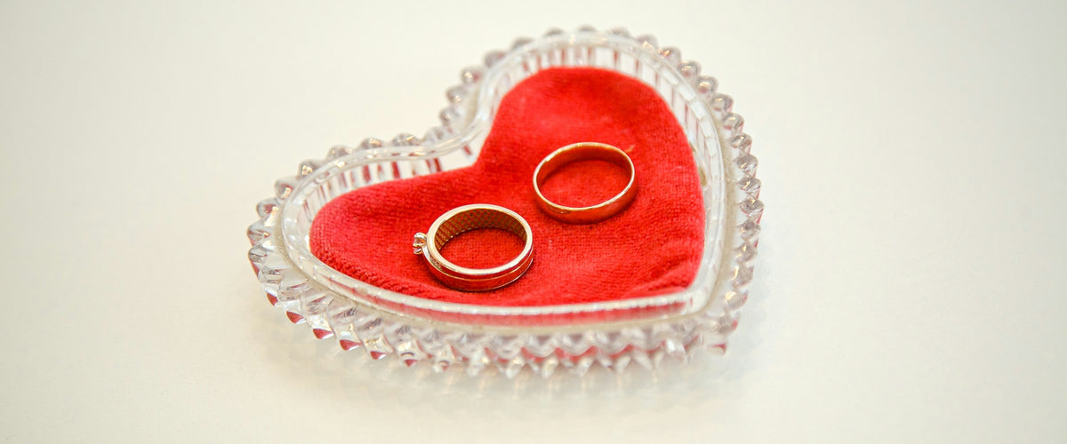 Pair of gold rings in a red heart-shaped ring dish